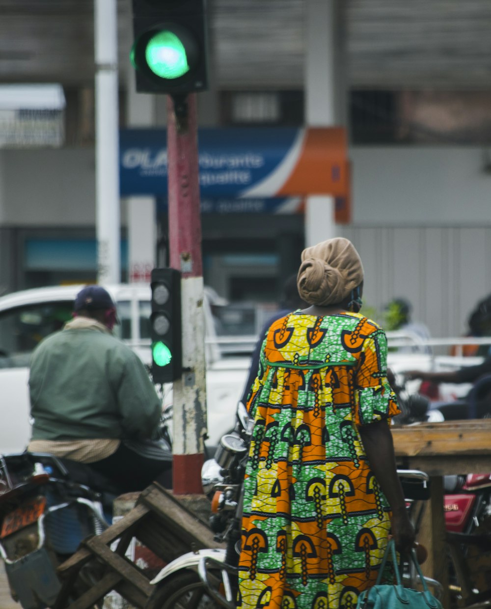 femme en robe à fleurs jaune, verte et blanche debout sur le trottoir pendant la journée