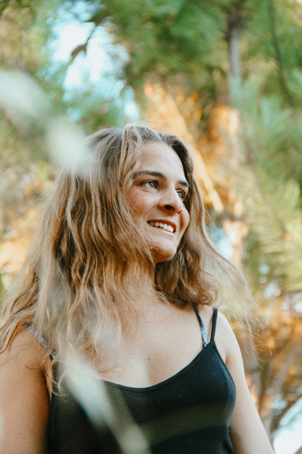 woman in black spaghetti strap top smiling