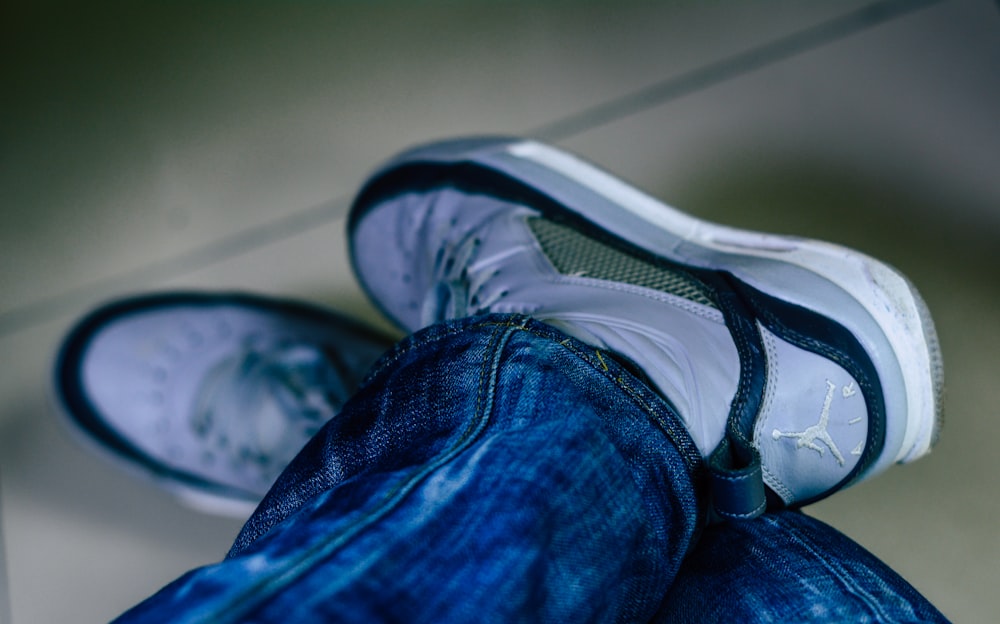 person in blue denim jeans and black and white nike athletic shoe