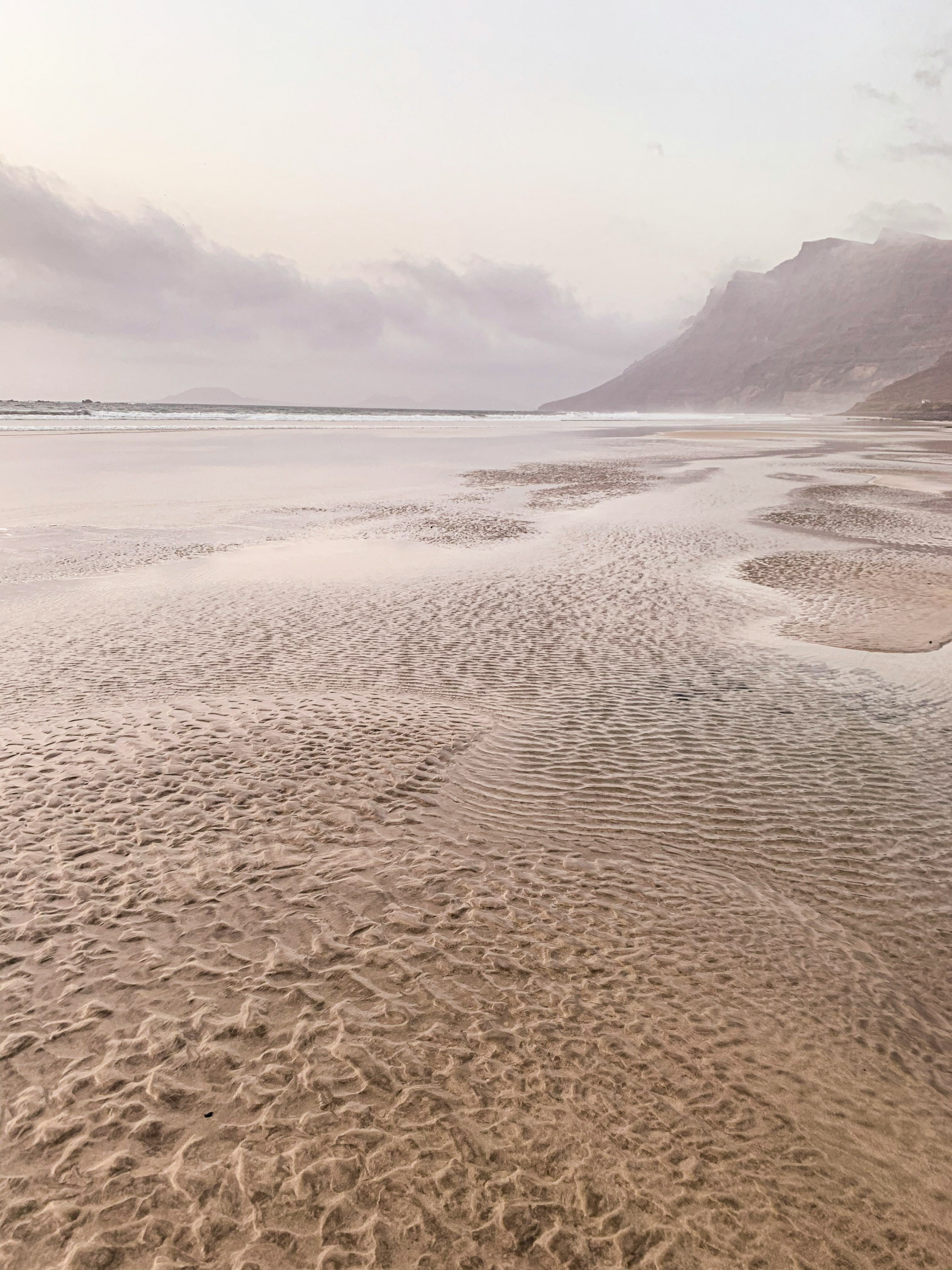 Famara beach, textured sand and volcanic mountains in the back