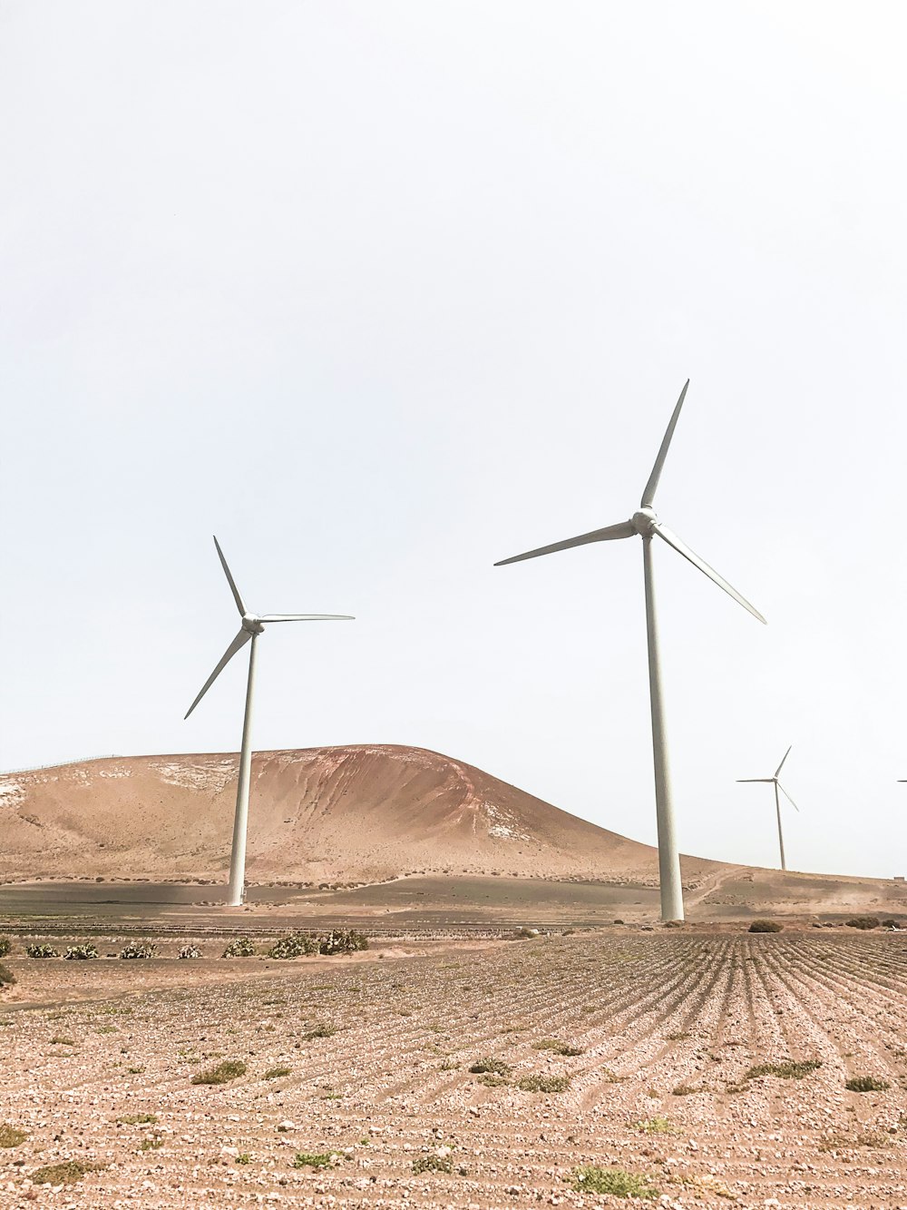 turbine eoliche su sabbia marrone sotto cielo bianco durante il giorno