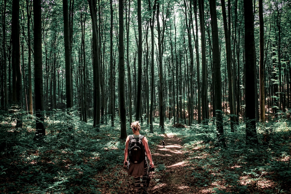 Donna in giacca marrone che cammina sulla foresta durante il giorno