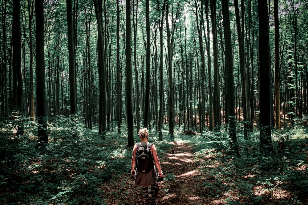 Mujer en chaqueta marrón caminando en el bosque durante el día