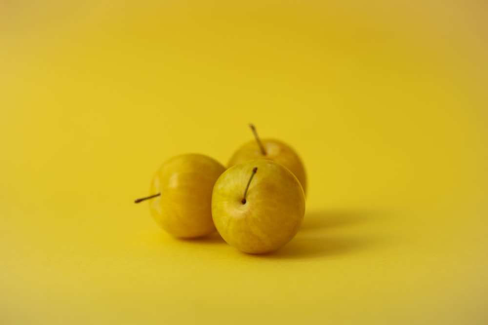 two green apples on yellow surface