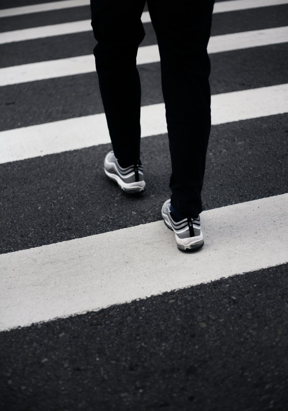 person in black pants and black and white nike sneakers