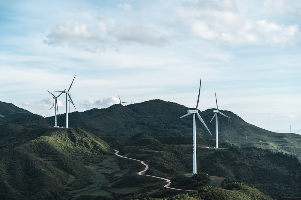 Weiße Windräder tagsüber auf grünem Rasenfeld unter weißem, bewölktem Himmel