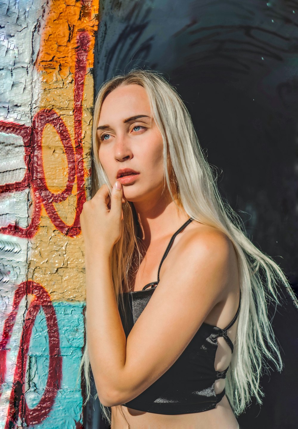 a woman posing in front of a graffiti wall