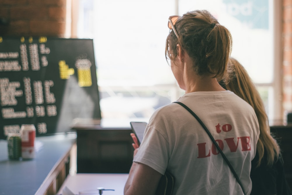 woman in white t-shirt looking at the window during daytime