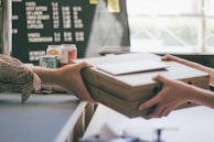 A close-up of hands exchanging shipping documents over a background of stacked fuel containers.