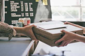 Hands exchanging a package over a counter in a retail environment.
