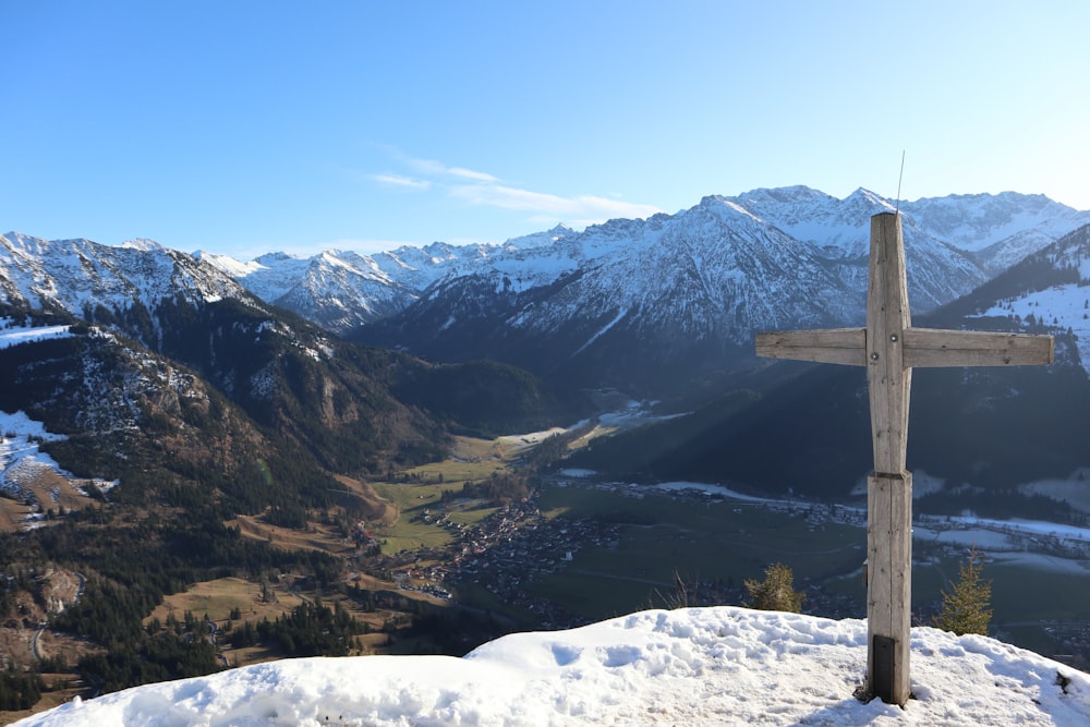 brown wooden post on snow covered ground near mountains during daytime