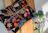 Bright, colorful postcards displayed on a rustic wooden table with splashes of watercolor paint around.