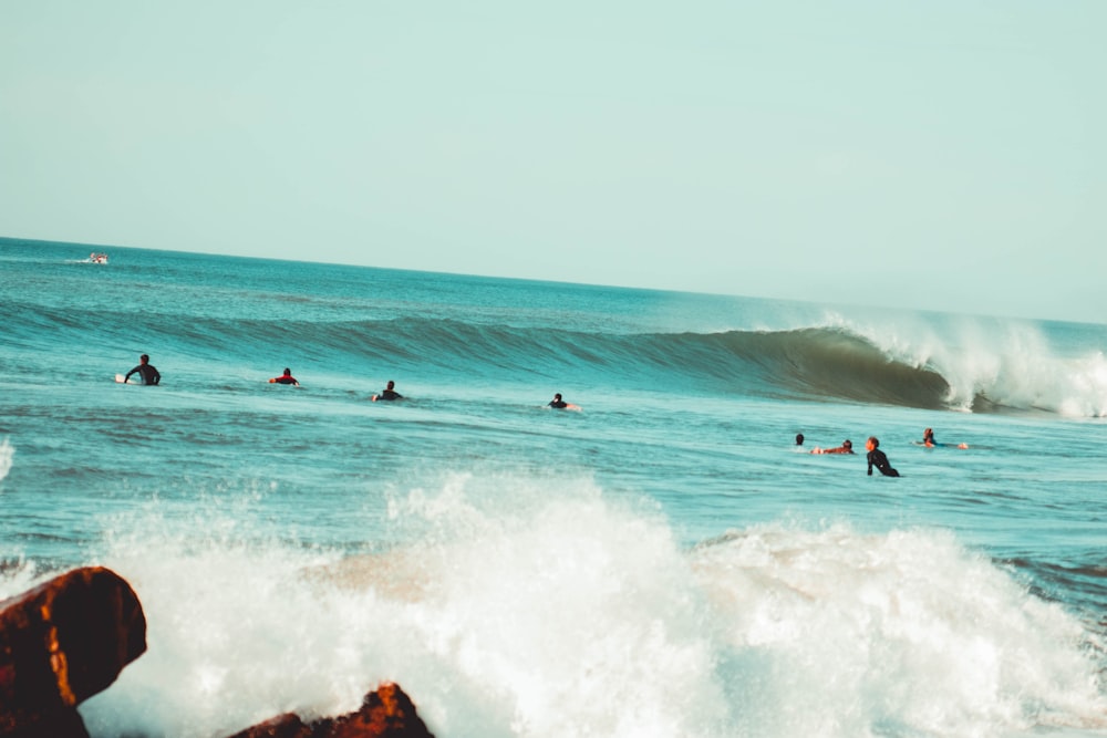 people surfing on sea waves during daytime