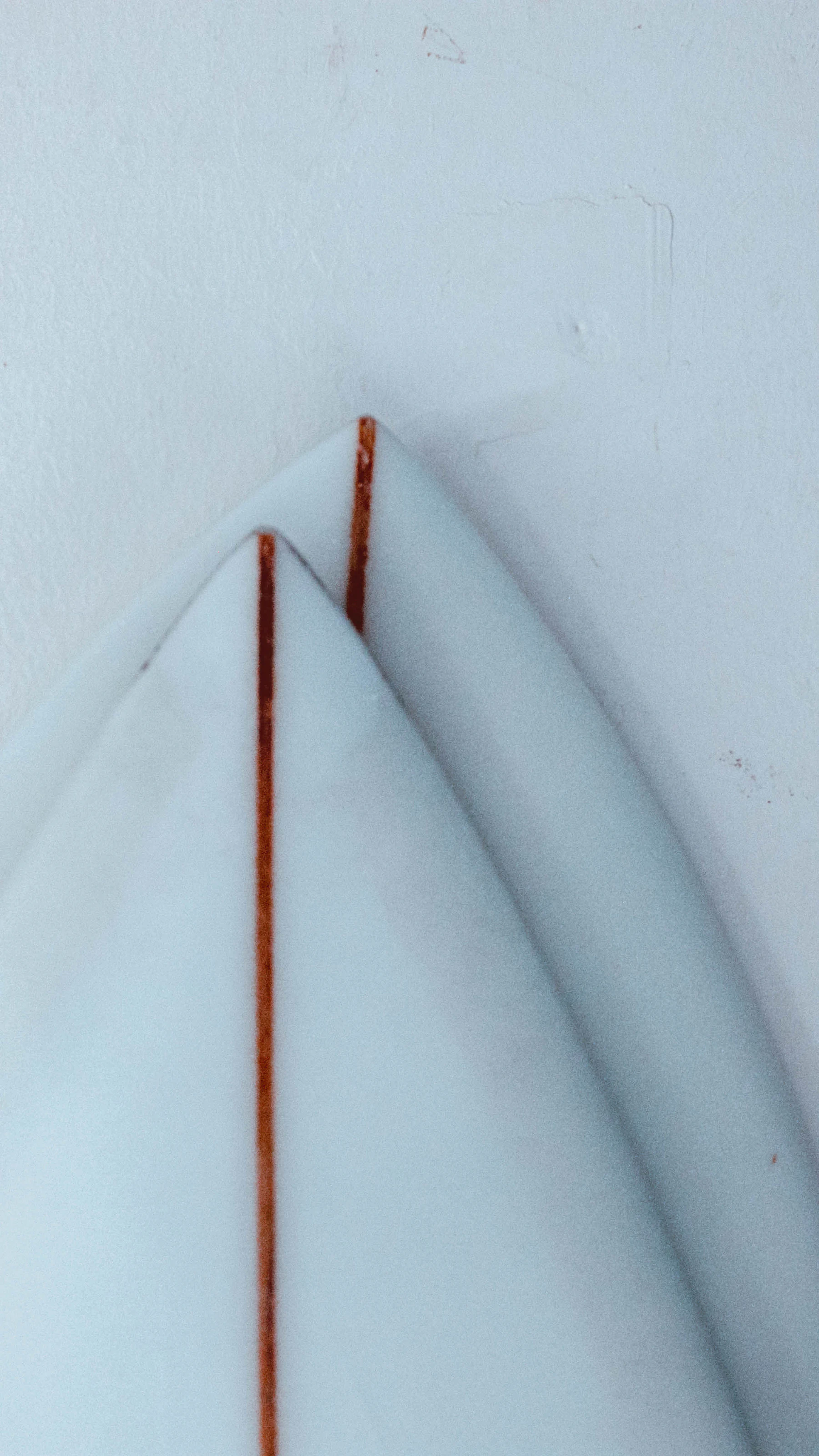 Two white foam surfboard blanks with red stringers, stacked nose to tail