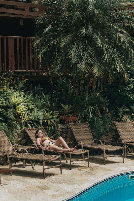 woman in black bikini lying on brown wooden bench in Bombinhas Brasil