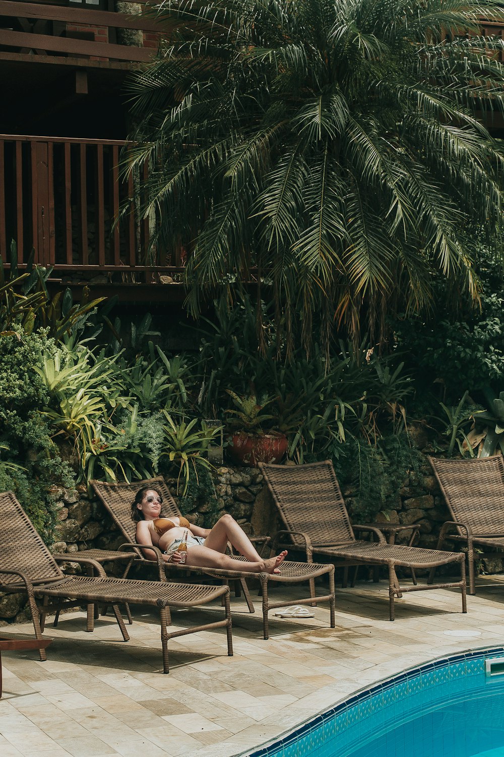 woman in black bikini lying on brown wooden bench