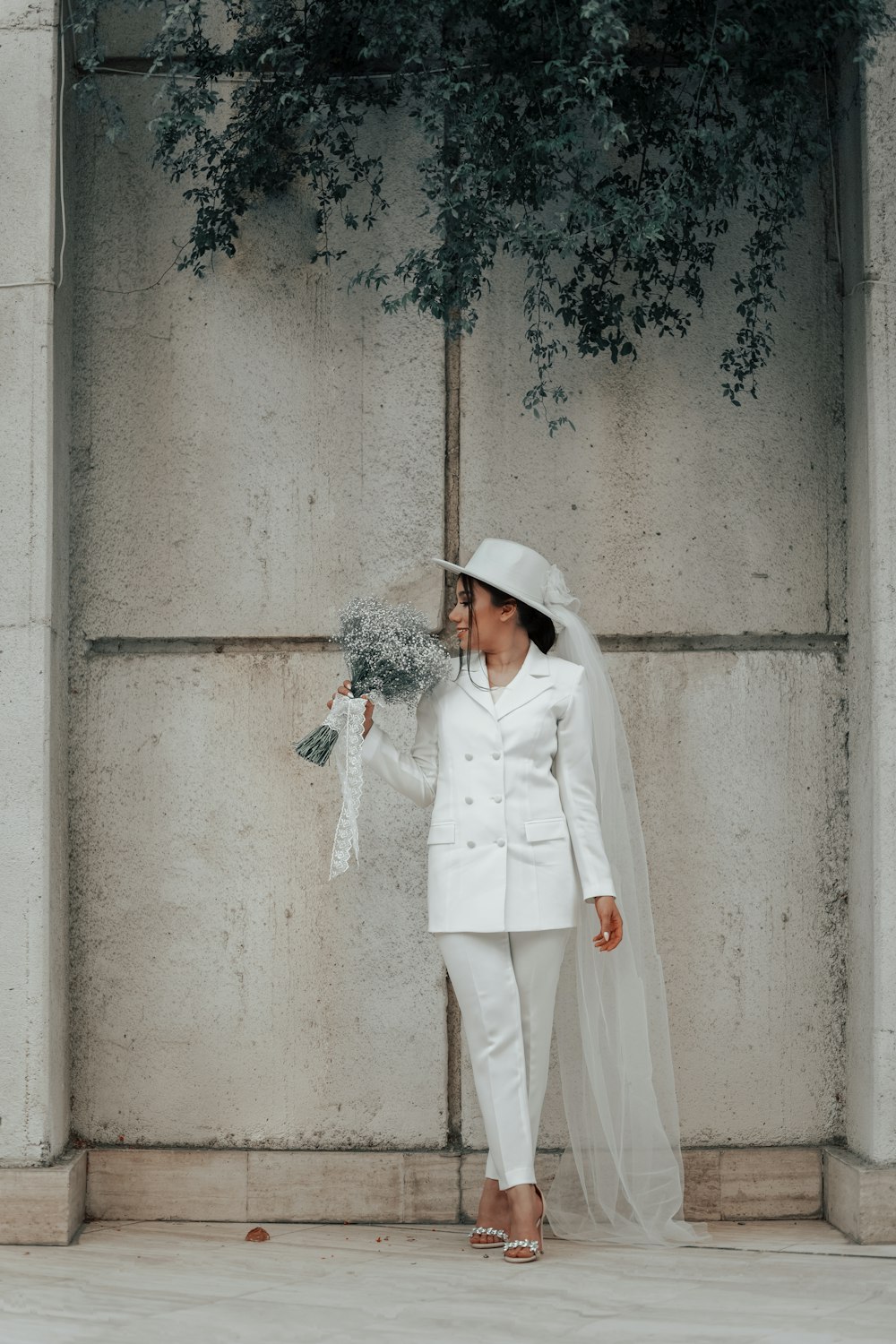 woman in white coat and white hat standing beside gray concrete wall