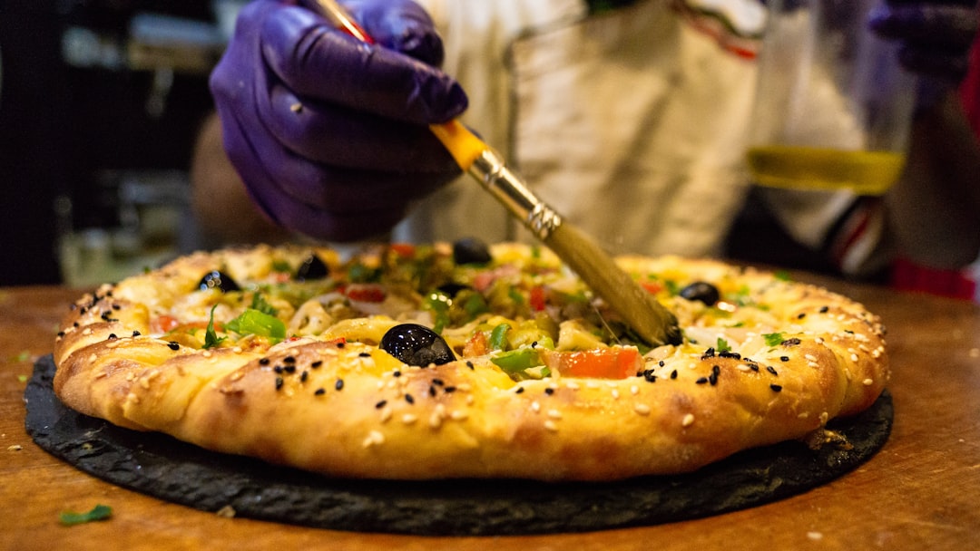 person holding a pizza with cheese and vegetable