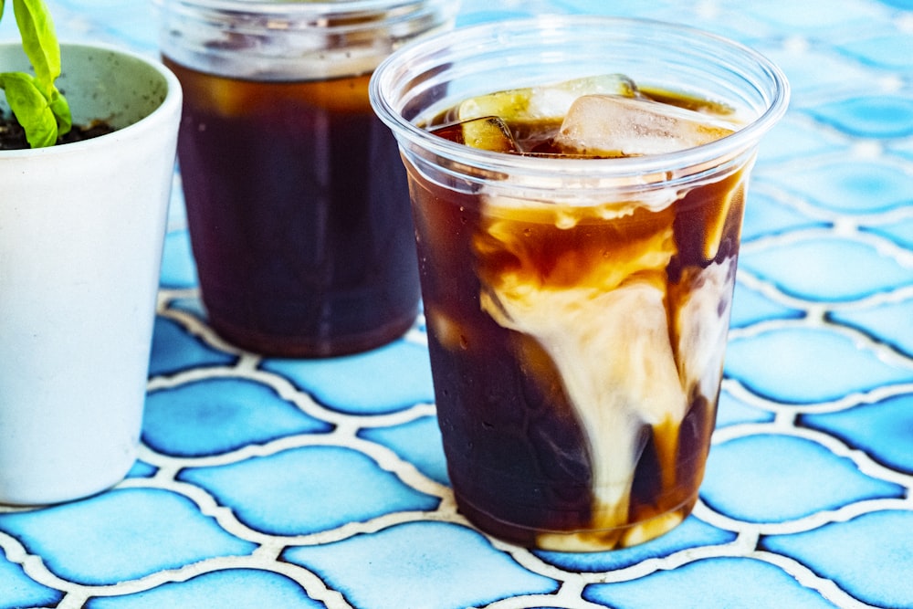 clear glass cup with ice and black liquid