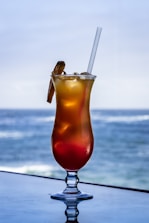 clear drinking glass with orange liquid and straw on white table