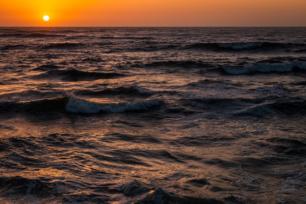 ocean waves crashing on shore during sunset