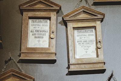 Two framed proclamations are displayed, each encased in wooden frames with glass fronts. The first decree bans all fireworks, while the second restricts the proximity of boys and girls to eight inches of each other. Metal chains are used to hang the frames.
