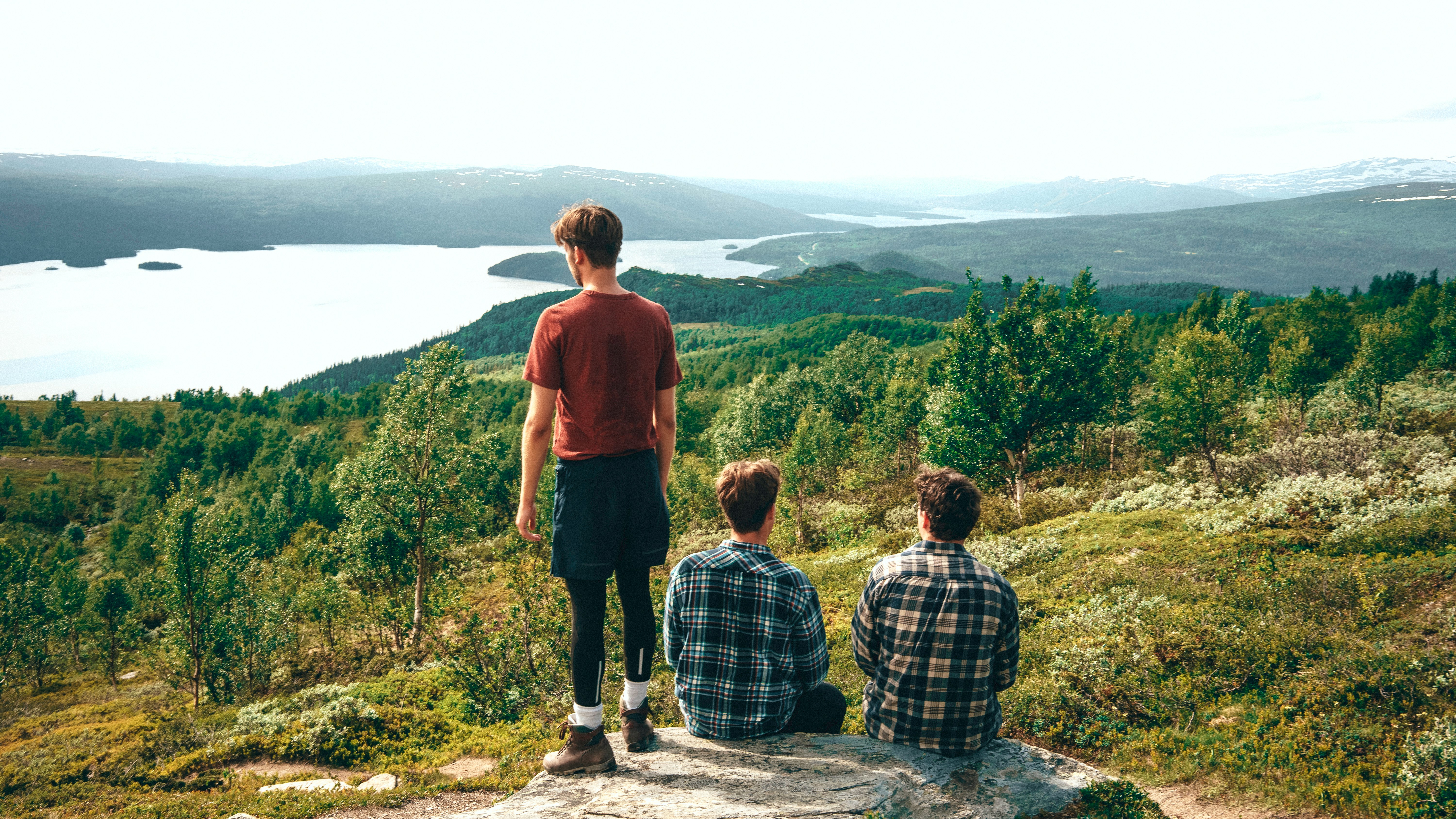 man in red t-shirt standing beside man in blue and white plaid dress shirt