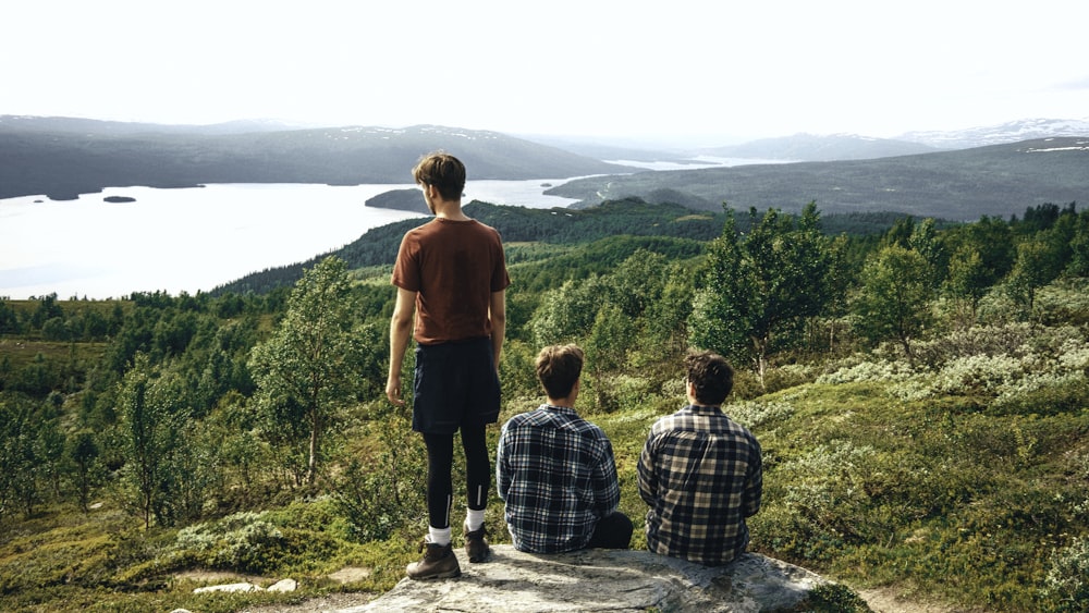 man in red t-shirt standing beside man in blue and white plaid dress shirt