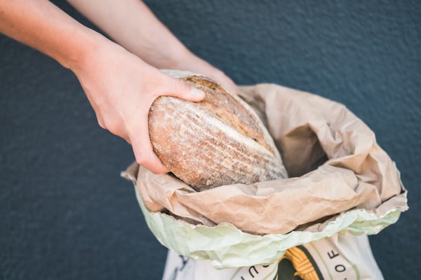 Baker handing a bag of fresh bread to a customer