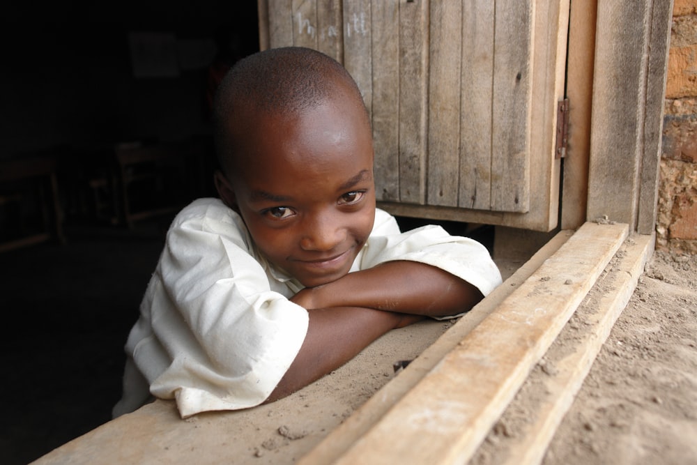 baby in white shirt lying on brown wooden floor