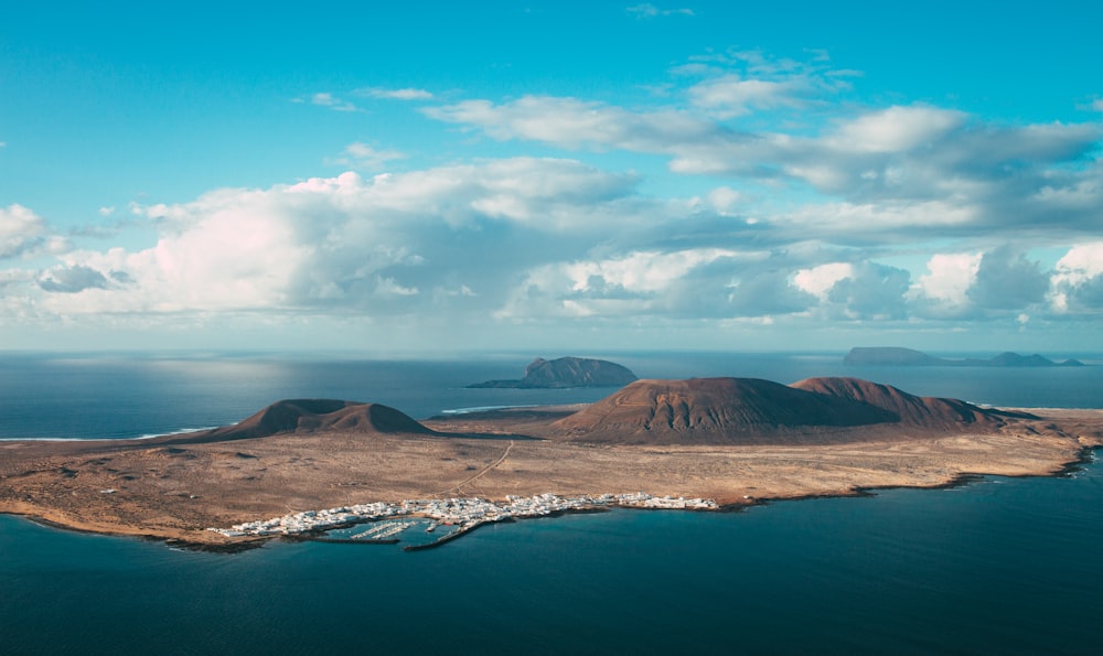 Brauner Berg in der Nähe von Gewässern unter blauem Himmel tagsüber