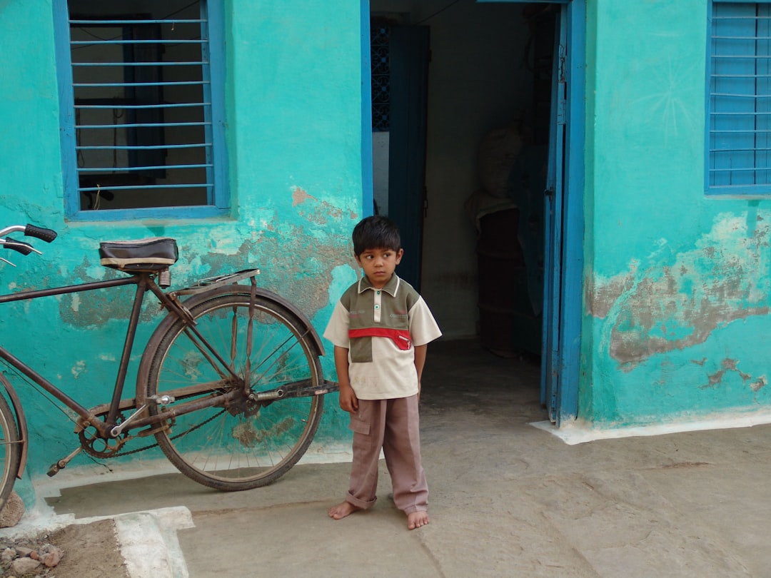 girl in white school uniform standing beside brown bicycle