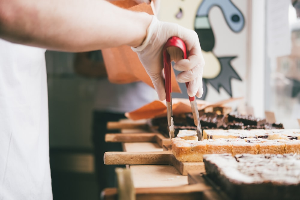 person holding brown wooden rolling pin