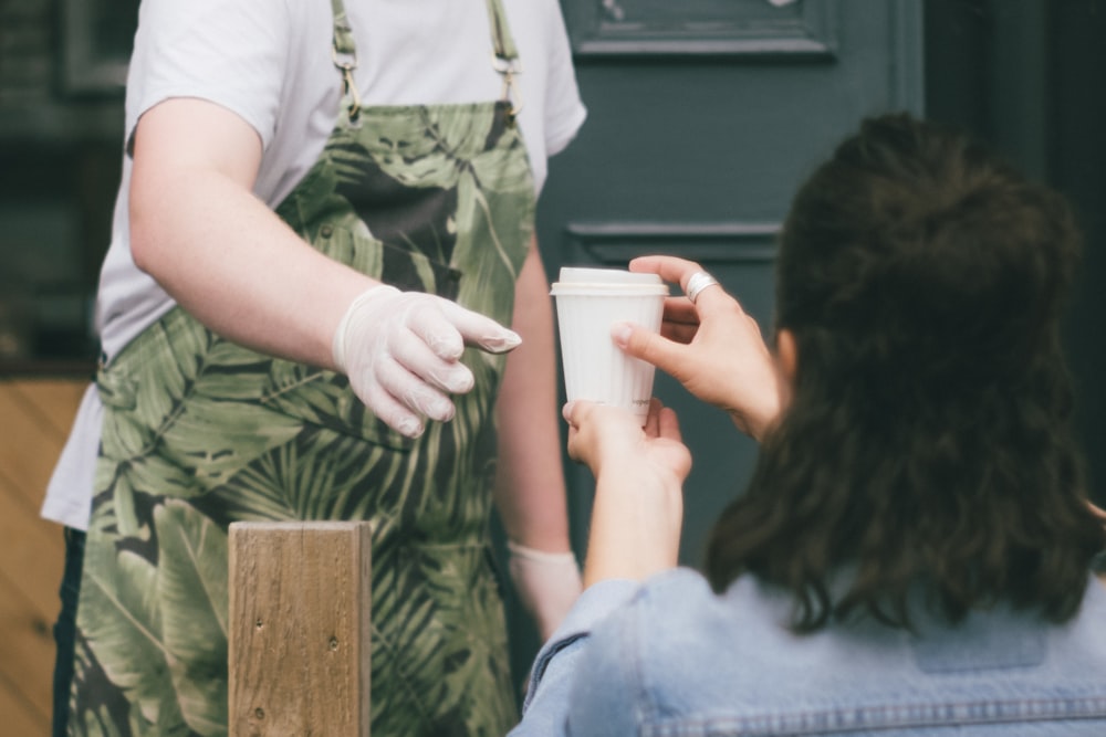 Femme en chemise blanche et jean bleu assise sur un banc en bois marron