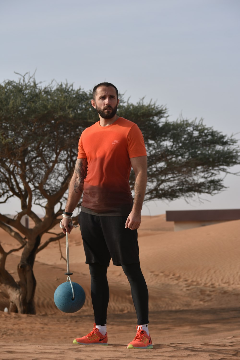 man in red polo shirt and black pants holding blue ball