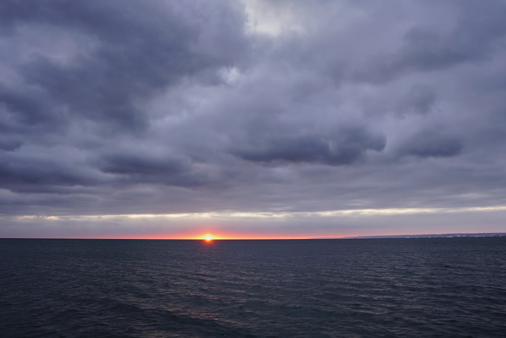 body of water under cloudy sky during sunset