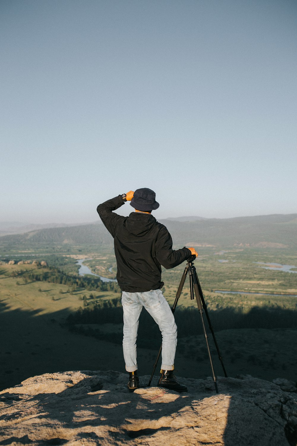 man in black jacket and white pants holding black dslr camera