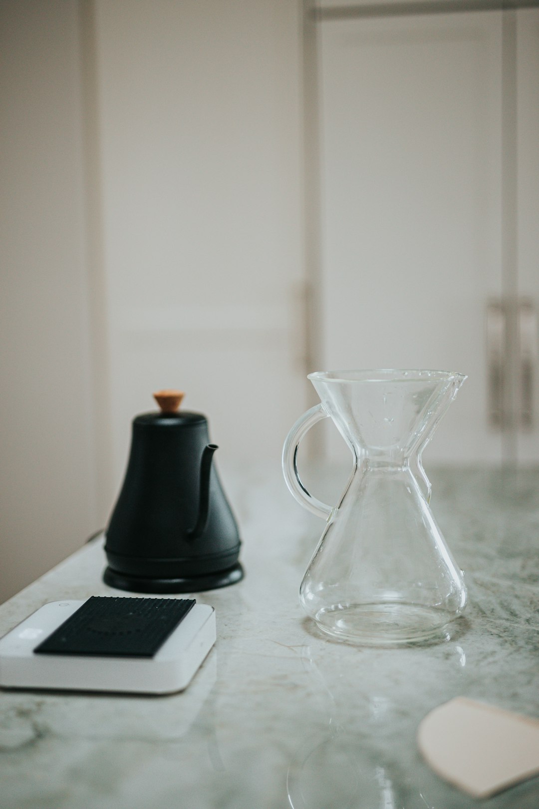 black ceramic teapot beside clear glass pitcher on white table