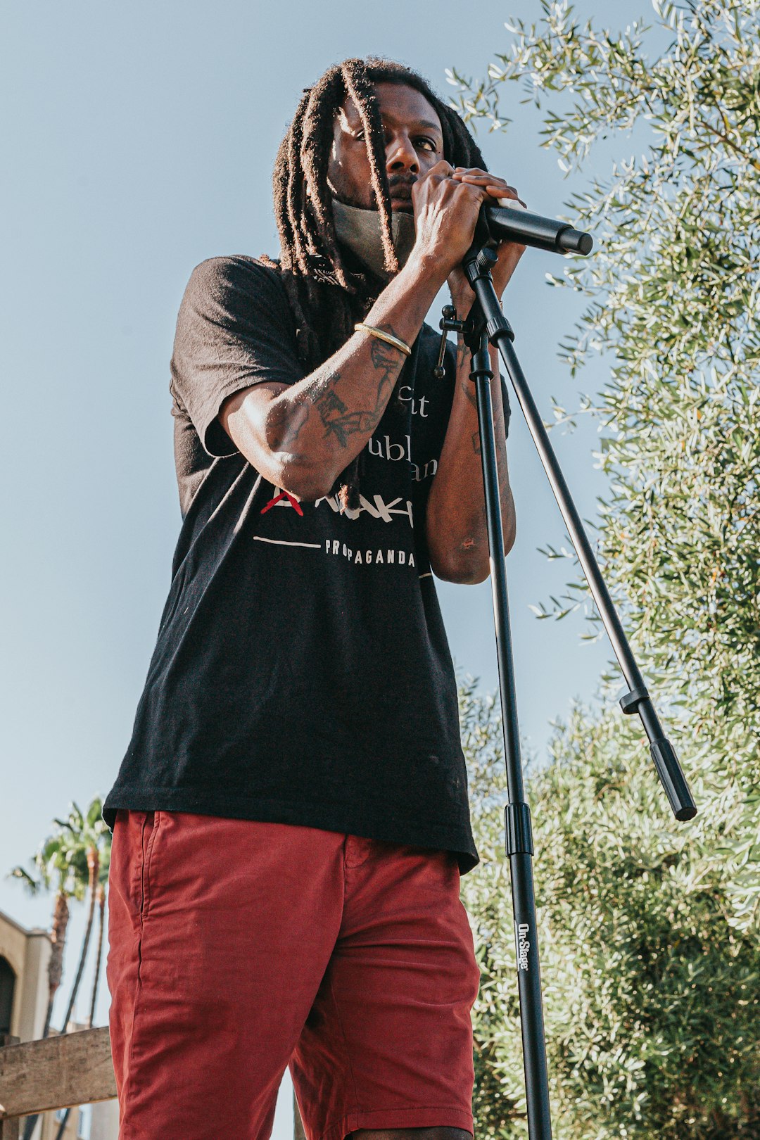 man in black t-shirt and red shorts holding black camera