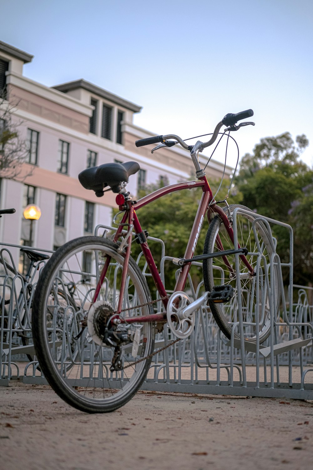 Bicicleta roja de la ciudad estacionada junto a la valla de metal blanca durante el día