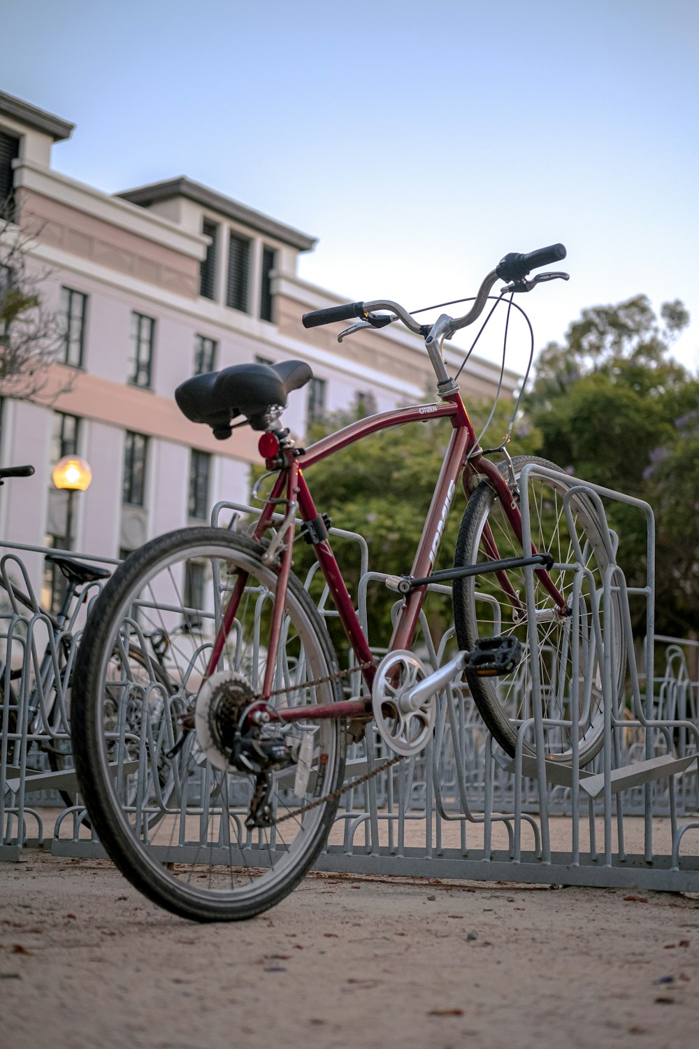 red city bike parked beside white metal fence during daytime