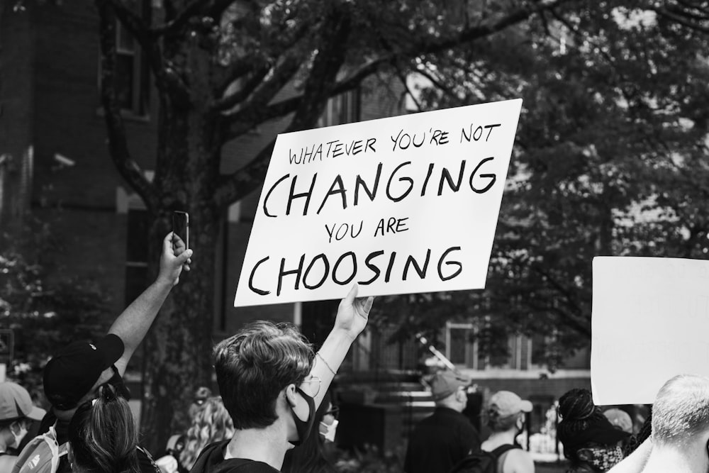 grayscale photo of people holding a signage