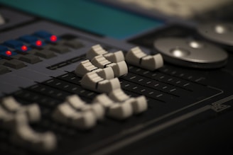 An audio mixing console with various controls and sliders.