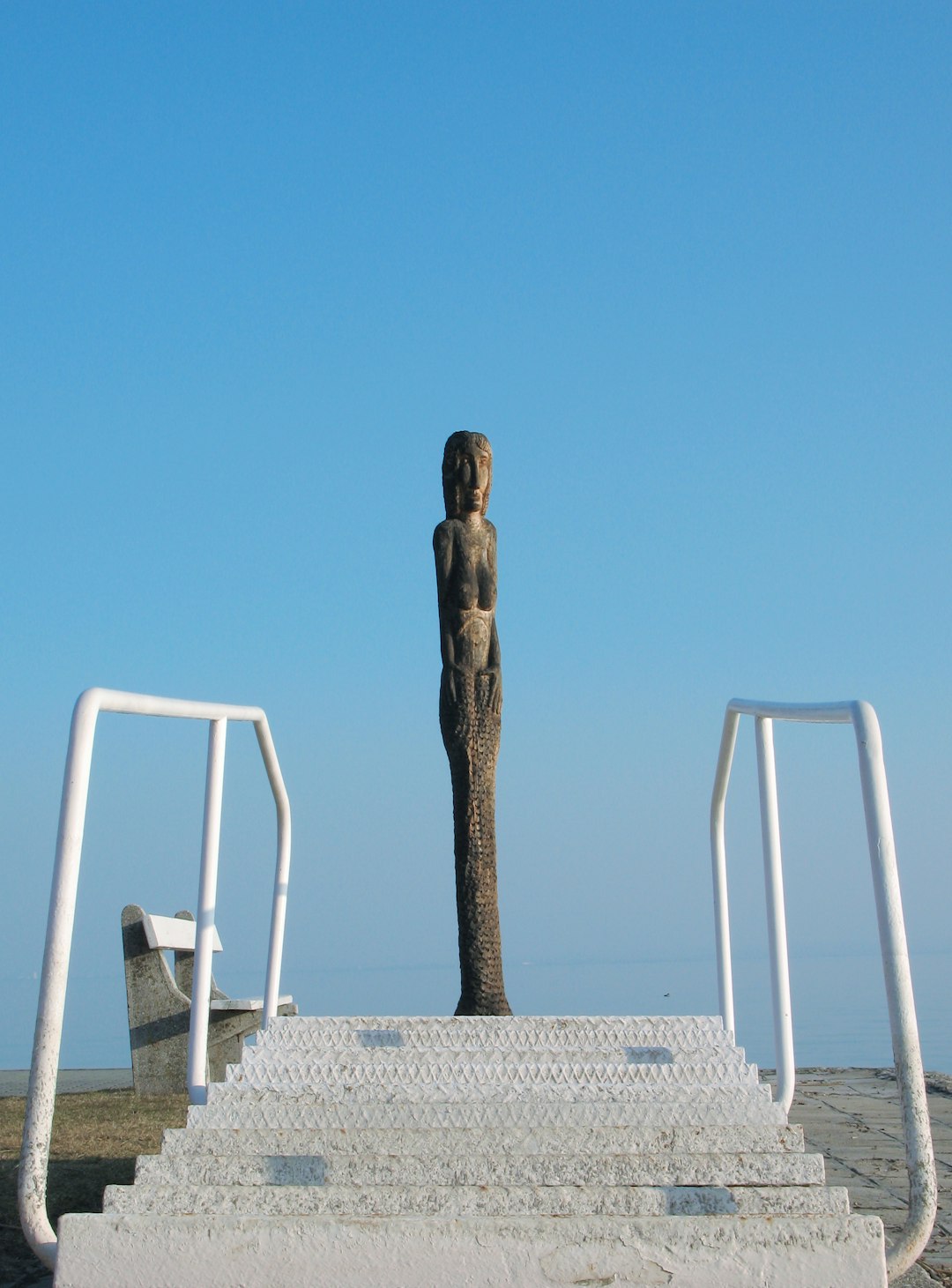 white wooden chair near statue under blue sky during daytime