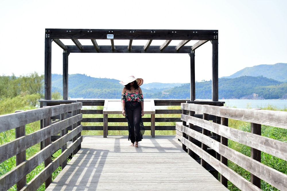 woman in black dress standing on wooden dock during daytime