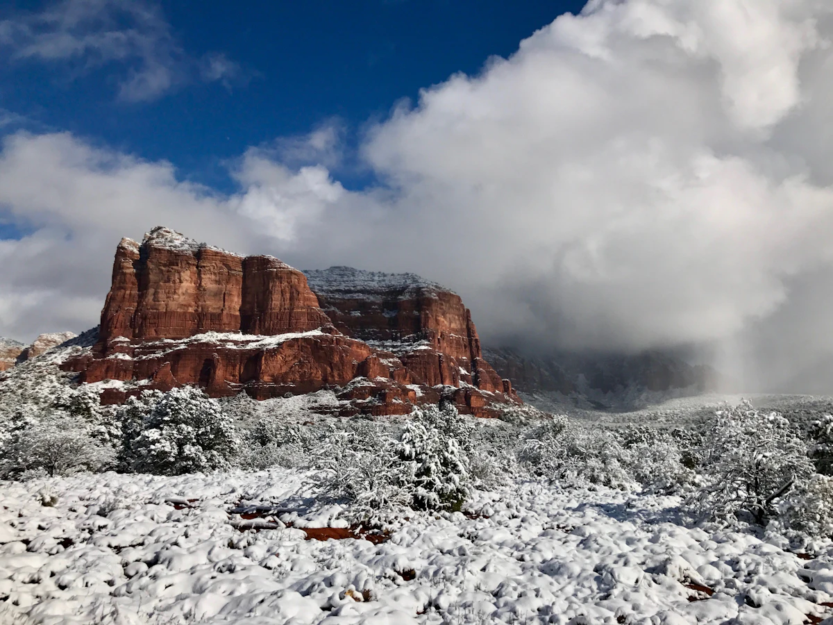 Red rock buttes dusted with snow under low cloud