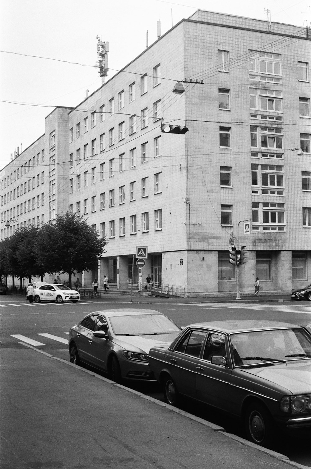 grayscale photo of cars parked beside building