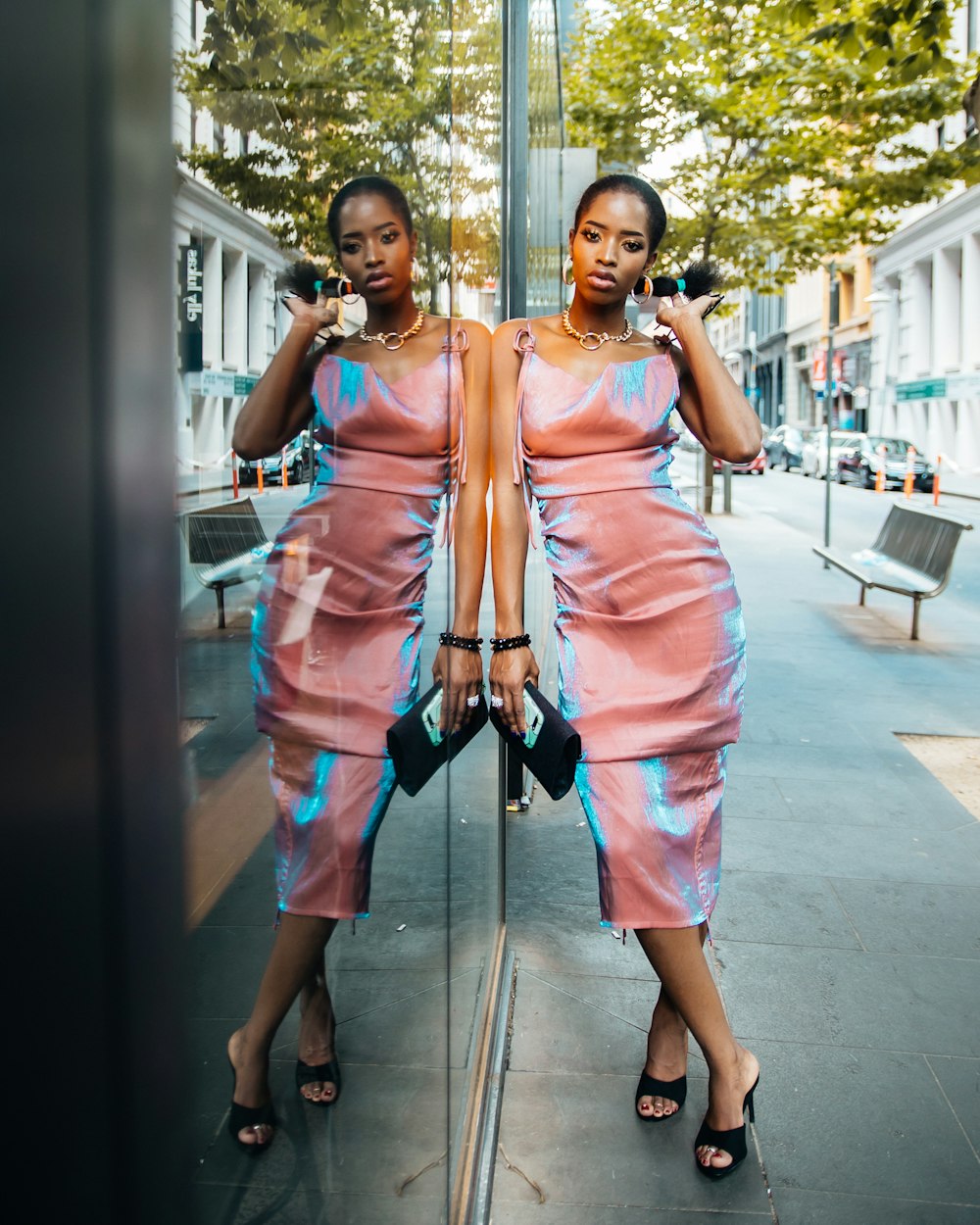 woman in orange sleeveless dress standing beside glass wall during daytime