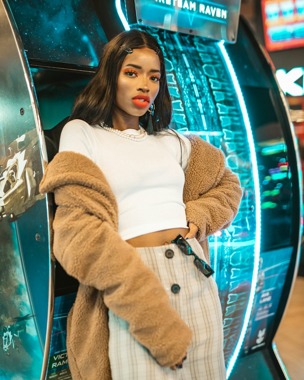 woman in white sweater and brown pants leaning on blue car