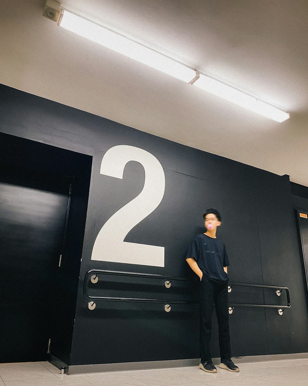 man in black suit standing beside black wooden door